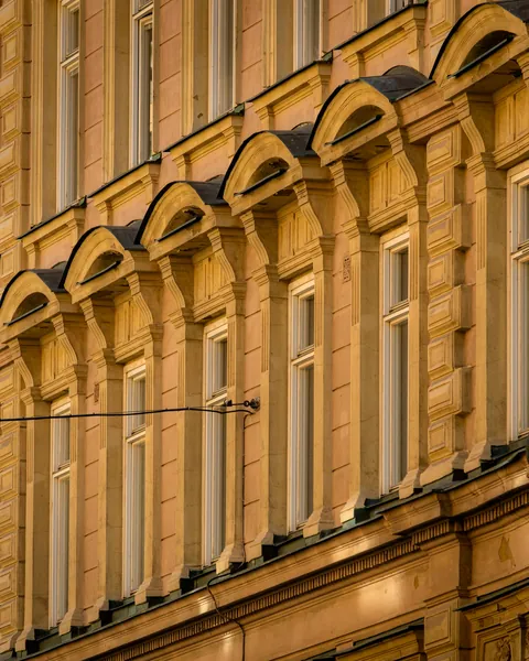 En stor stenfasad i ockra med rader av fönster och utsmyckningar.